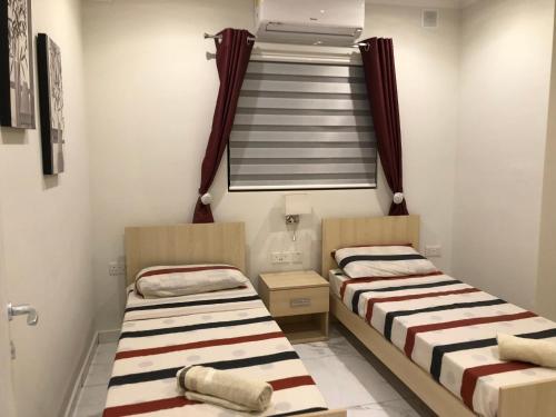 two beds in a small room with a window at Marsascala Sea View Apartment & Penthouse in Marsaskala