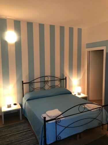ロッサーノにあるB&B CasAmicaのベッドルーム1室(ストライプの壁とランプ2つ付)