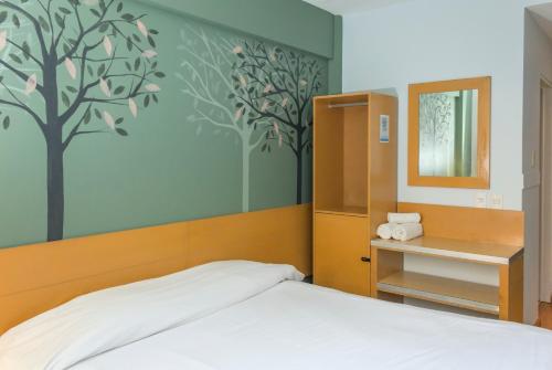 a bedroom with a bed with a tree mural on the wall at Circus Hostel in Buenos Aires
