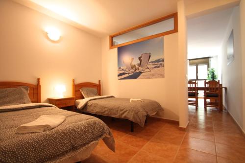 a bedroom with two beds and a table and chairs at Pont de Toneta 3,2 Ransol, Zona Grandvalira in Ransol