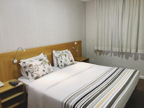 una camera da letto con un grande letto bianco con due cuscini di Marsala Apart Hotel a Mogi das Cruzes