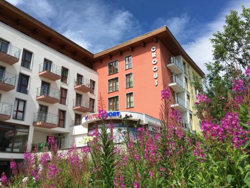 un hotel con fiori rosa di fronte di Apartmán Crocus 313 a Štrbské Pleso