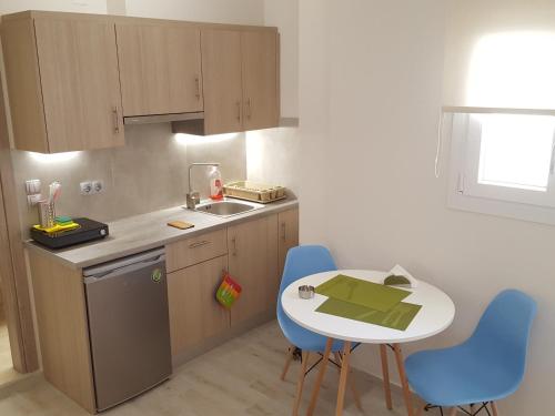 a small kitchen with a small table and blue chairs at Minimalistic Studio Apartments in Heraklio Town