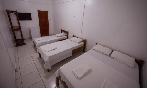 a small room with three beds and a mirror at Hotel Holliday in Macapá