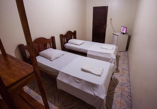 two beds in a small room with a refrigerator at Hotel Holliday in Macapá