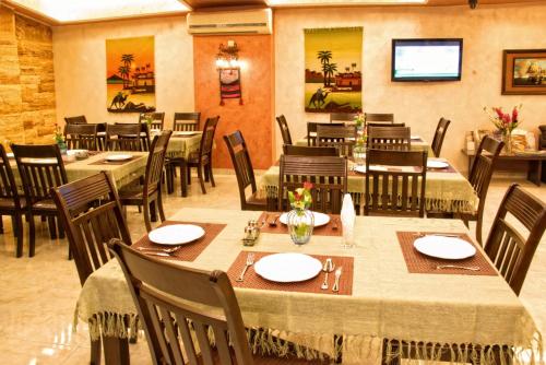 un restaurant avec des tables et des chaises et une télévision dans l'établissement Jardaneh Hotel, à Aqaba