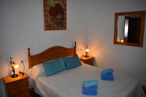 a bedroom with a bed with blue cushions and two lamps at El Mirador in Iznájar