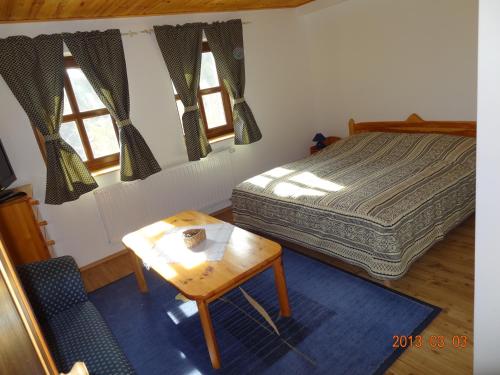a bedroom with a bed and a table and two windows at Szél Fiai Fogadó in Nyúl
