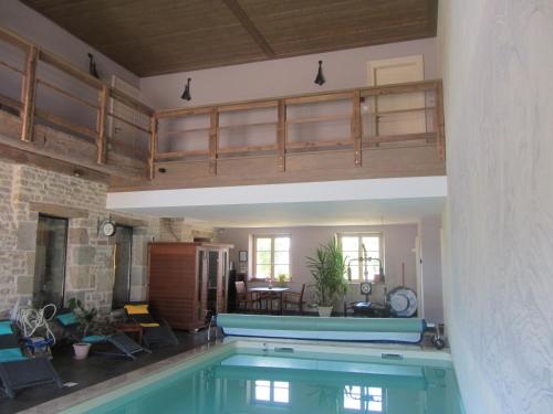 a large swimming pool in a living room with a house at Le relais des deux tours in Brémondans