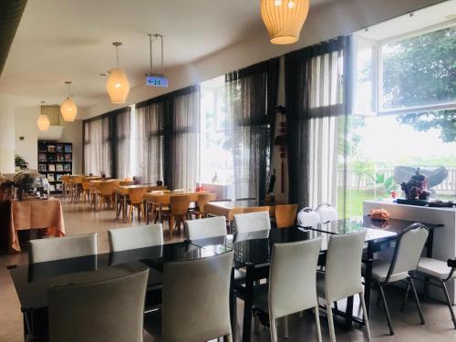 a dining room with tables and chairs and large windows at Zhi Da Craft Service Guest House in Caotun