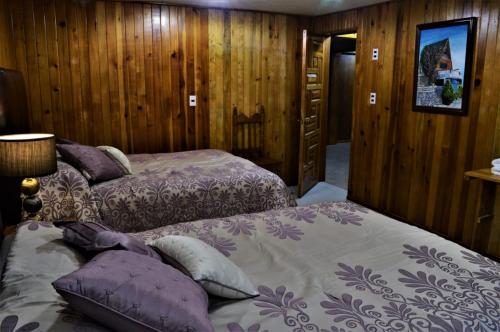 two beds in a room with wooden walls at Hotel "La Cabaña de Don Adolfo" in Zacatlán