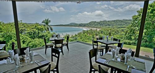 a restaurant with tables and chairs and a view of the ocean at Nammbú Beach Front Bungalows in Sámara