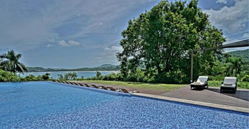 a swimming pool with two lounge chairs and the water at Nammbú Beach Front Bungalows in Sámara