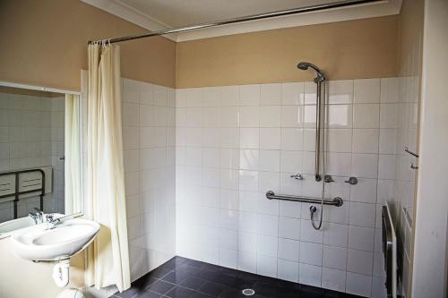 La salle de bains est pourvue d'un lavabo et d'une douche. dans l'établissement The Gallery Motor Inn, à Dalby