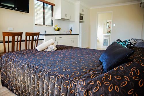 a bedroom with a bed with a blue comforter at The Gallery Motor Inn in Dalby