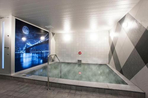 a bath tub in a room with a large window at DEL style Nagoya Nayabashi by Daiwa Roynet Hotel in Nagoya