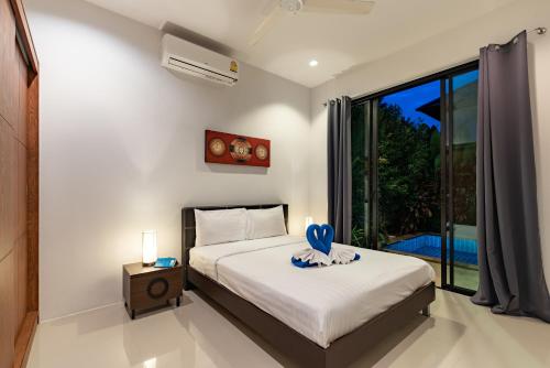 ein Schlafzimmer mit einem Bett und einem großen Fenster in der Unterkunft Modern 3br Boutique Pool Villa by Intira Villas in Rawai Beach