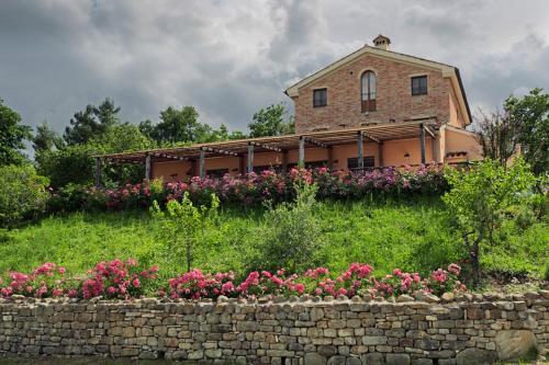 dom z kwiatami przed kamienną ścianą w obiekcie Agriturismo Agra Mater w mieście Colmurano