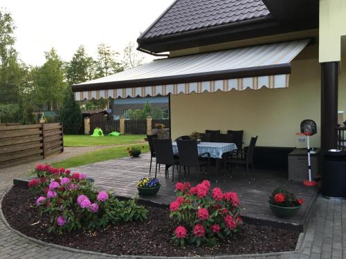 a patio with a table and chairs and flowers at Vila Laurus in Palanga
