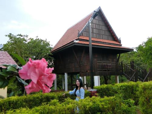 a woman standing in front of a house with a pink flower at Greenhouse Retreat in Sen Monorom