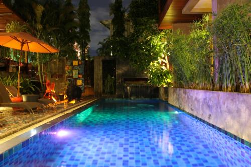 a swimming pool in a backyard with an umbrella at Villa Thapae in Chiang Mai