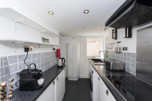 a kitchen with white cabinets and black counter tops at Sea Front Walk in Broadstairs