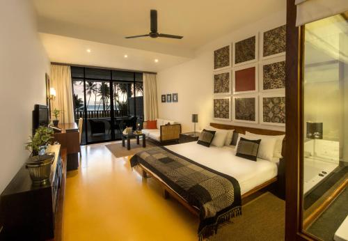 a bedroom with a bed and a living room at The Blue Water - Geoffrey Bawa Heritage Resort Hotel in Wadduwa