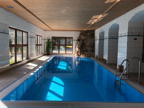 a swimming pool with blue water in a building at Berghotel Friedrichshöhe in Kurort Altenberg
