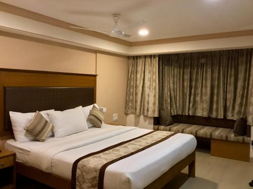 a hotel room with a large bed and a window at Sai Towers in Puttaparthi