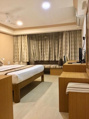 a hotel room with two beds and a window at Sai Towers in Puttaparthi