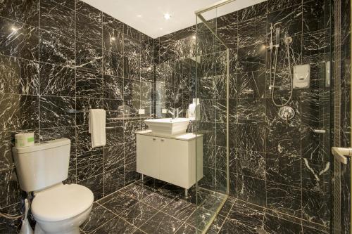 a black tiled bathroom with a toilet and a shower at The Chermside Apartments in Brisbane