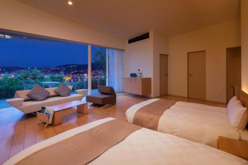 a hotel room with two beds and a large window at Garden Terrace Nagasaki Hotels & Resorts in Nagasaki