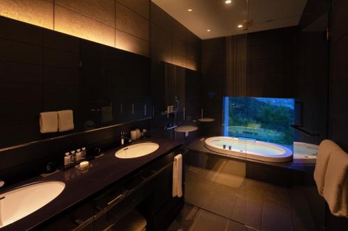a bathroom with two sinks and a tub with a window at Garden Terrace Nagasaki Hotels & Resorts in Nagasaki