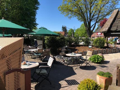 a patio with tables and chairs with umbrellas at Hotel Wardenburger Hof in Wardenburg
