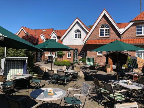 a patio with tables and umbrellas in front of a building at Hotel Wardenburger Hof in Wardenburg