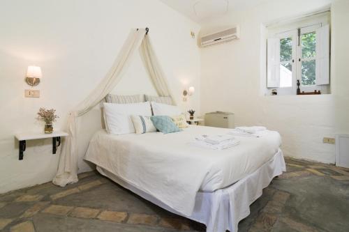 a white bedroom with a white bed with a canopy at Castello di Serragiumenta in Firmo