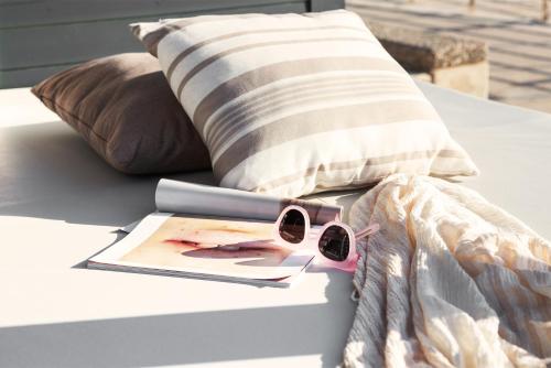 a pair of sunglasses sitting on a bed with a pillow at Sunprime Protaras Beach - Adults Only in Protaras