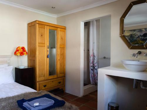 a bathroom with a bed and a sink and a mirror at EpiStay in Tulbagh