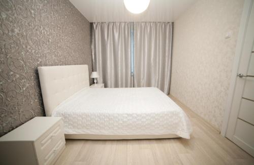 een slaapkamer met een wit bed en een raam bij Alekseyeva Apartament in Krasnojarsk
