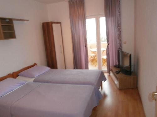 a bedroom with two beds and a tv and a window at Apartment Maja in Vodice