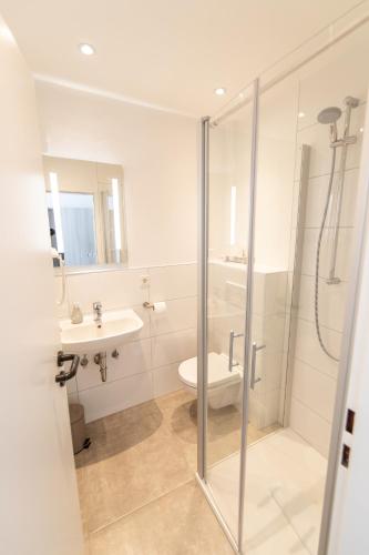 a bathroom with a shower and a toilet and a sink at Hotel Angelo in Saarbrücken