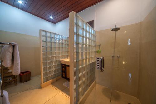 ein Bad mit einer Dusche und einer Glasduschkabine in der Unterkunft Villa Este in Seminyak