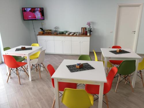 a dining room with white tables and colorful chairs at La Formica in Civitavecchia
