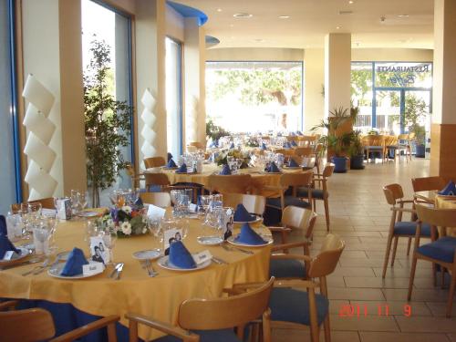 - une salle à manger avec des tables, des chaises et des serviettes bleues dans l'établissement Hotel Rober Palas, à Albir