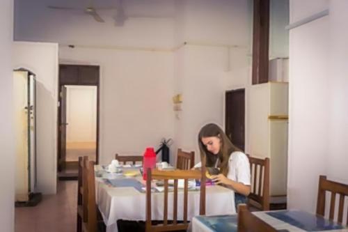 桑給巴爾的住宿－Karibu Inn，坐在桌子旁看着手机的女人
