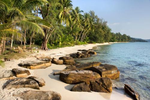 a beach with rocks and palm trees and the ocean at Shantaa Resort, Kohkood in Ko Kood