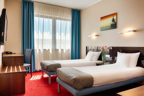 a hotel room with two beds and a window at Focus Hotel Gdańsk in Gdańsk
