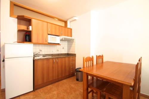 a kitchen with a wooden table and a white refrigerator at Pont de Toneta 3,4 Ransol, Zona Grandvalira in Ransol