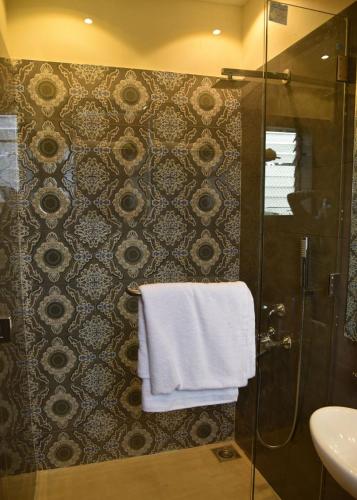 a bathroom with a shower and a white towel at Creek Hotel - Panaji in Panaji