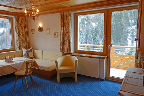 Zimmer mit einem Bett, einem Tisch und Fenstern in der Unterkunft Alkira in Sankt Anton am Arlberg
